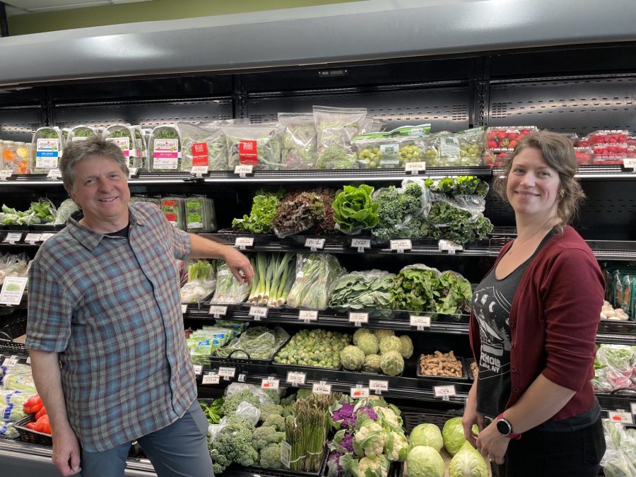 Two people stand in front of displayed produce