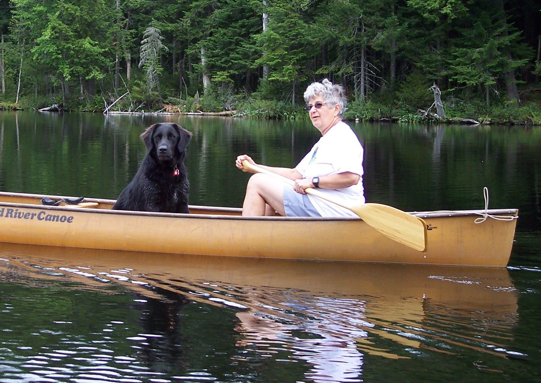 woman rides in a canoe with a dog